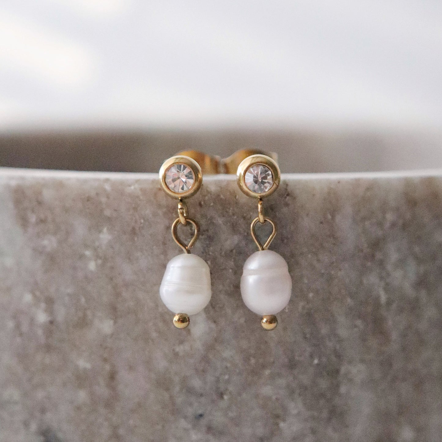 Pearl earrings with gold accents on a marble surface