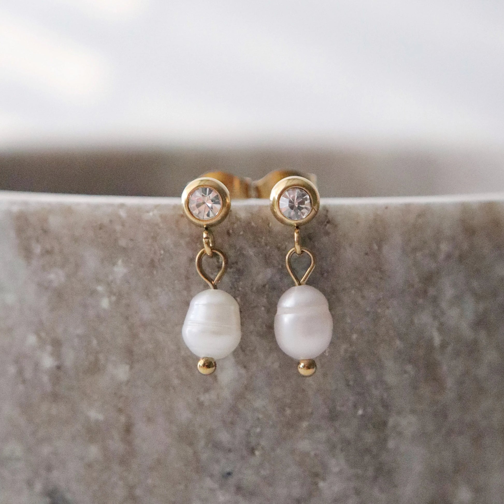 Pearl earrings with gold accents on a marble surface