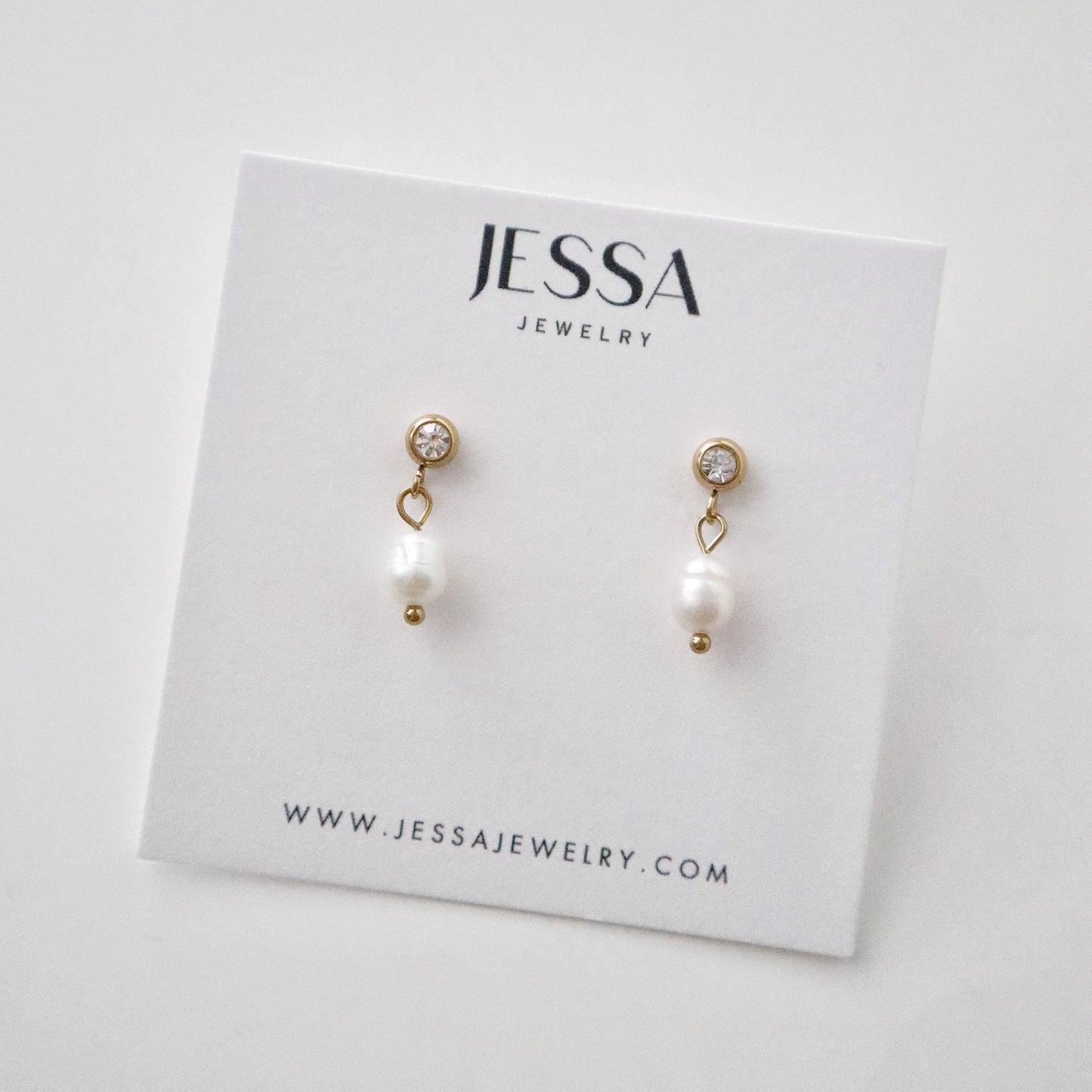 Pearl earrings on a Jessa Jewelry card with a white background