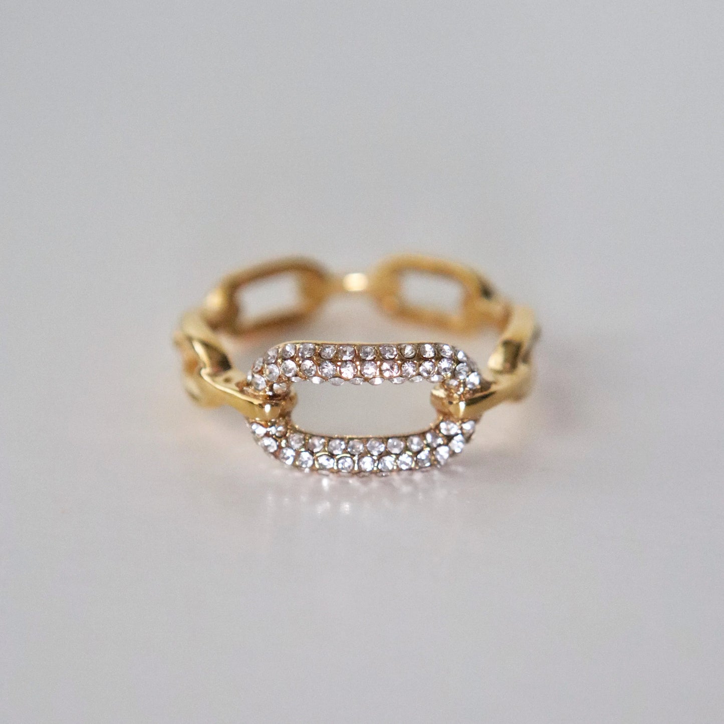 Gold ring with diamond accents on a light gray background