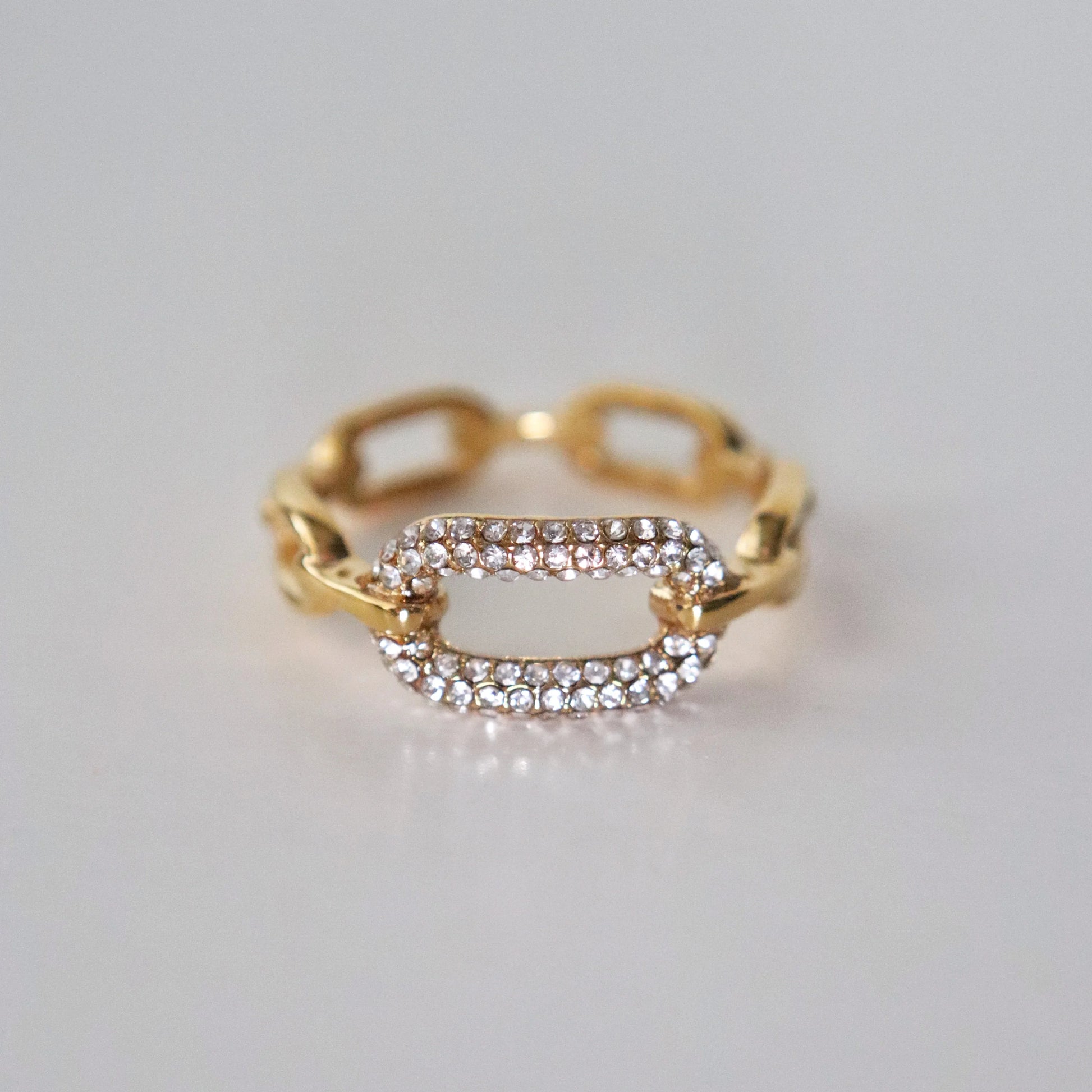 Gold ring with diamond accents on a light gray background