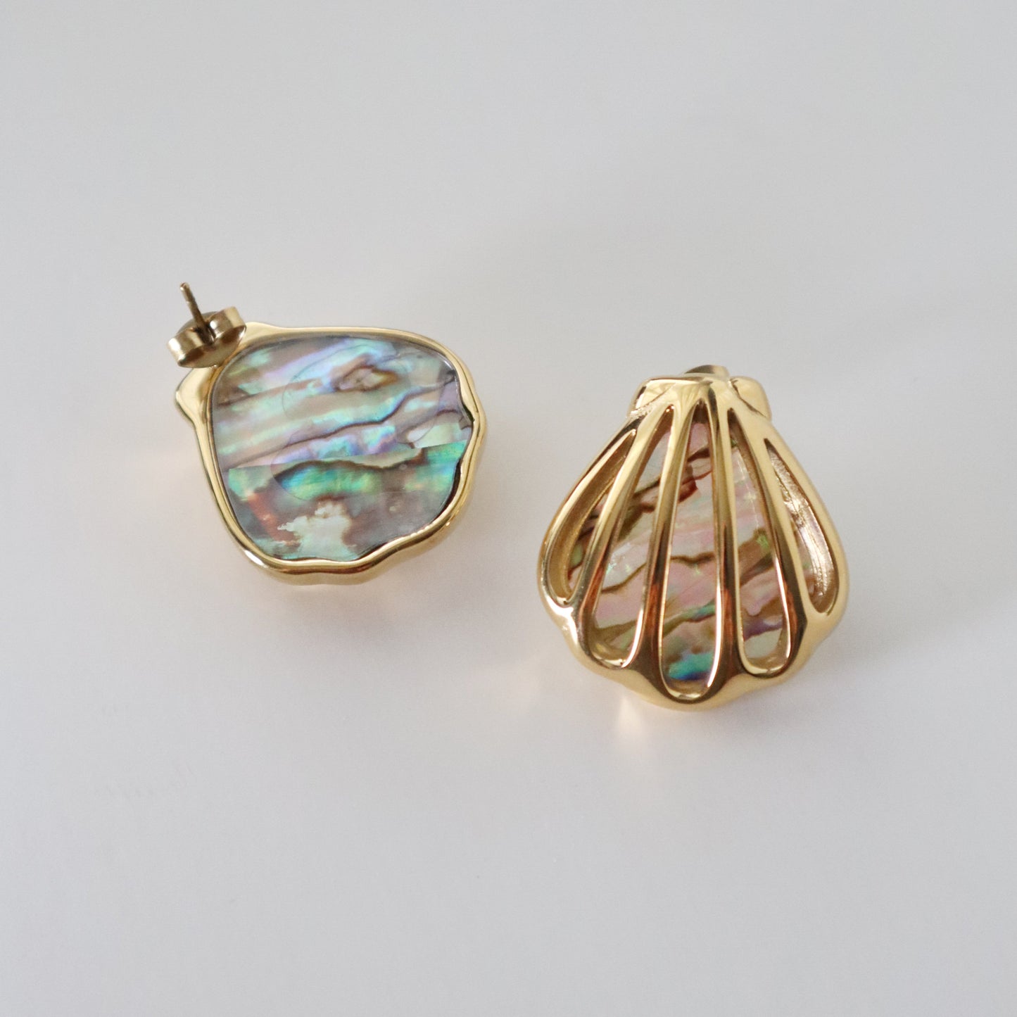 Gold earrings with abalone shell design on a light gray background