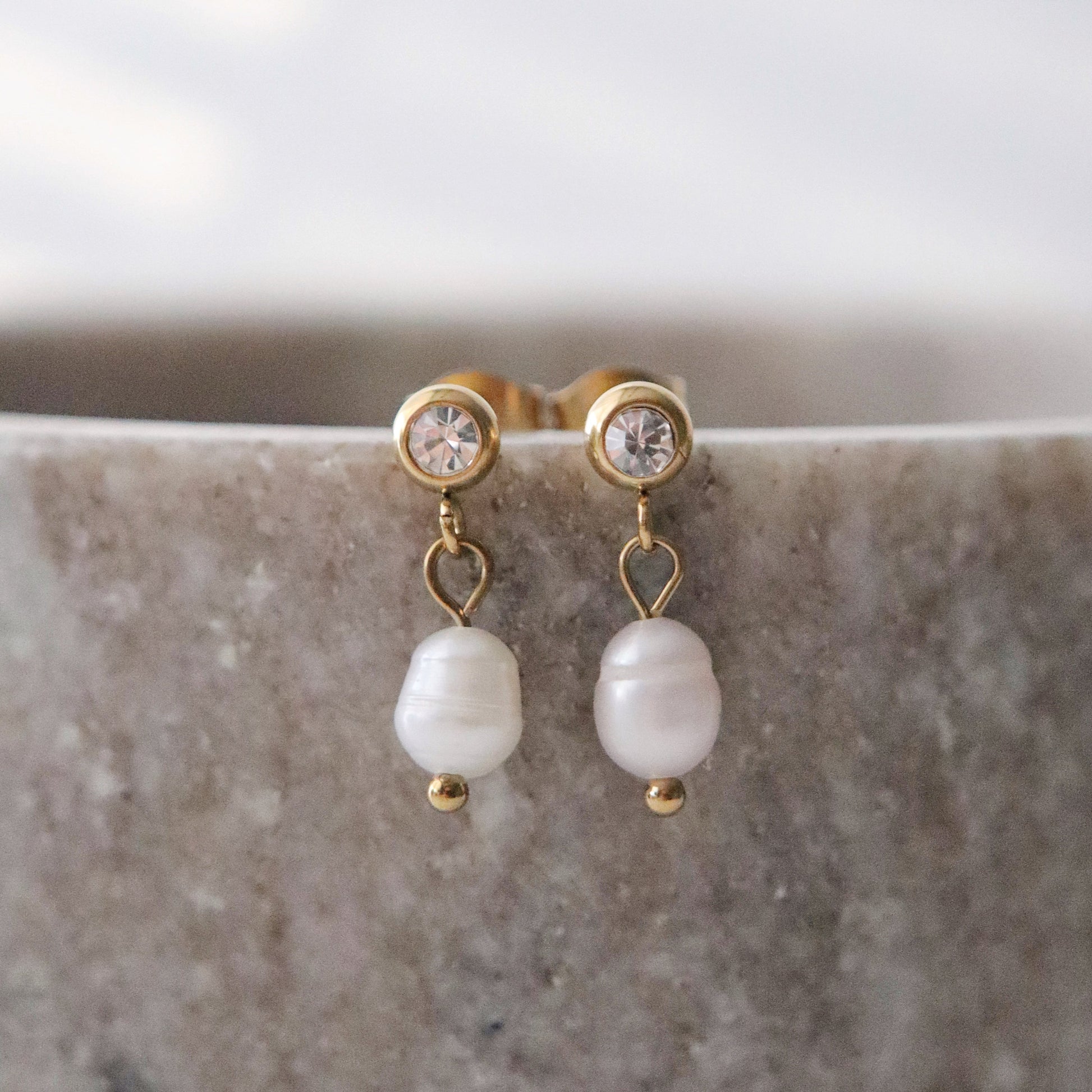 Pearl earrings with gold accents on a marble surface