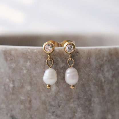 Pearl earrings with gold accents on a marble surface