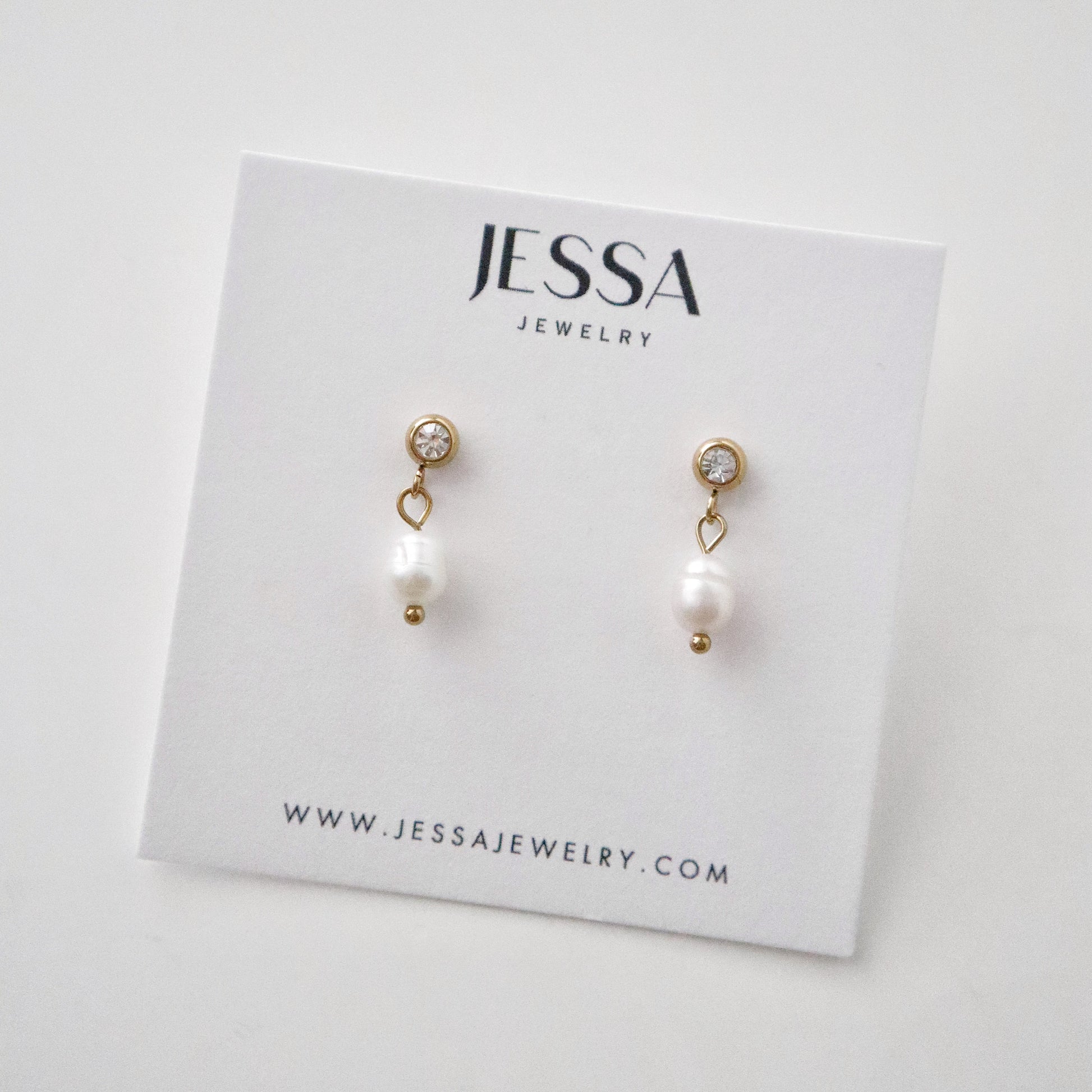 Pearl earrings on a Jessa Jewelry card with a white background