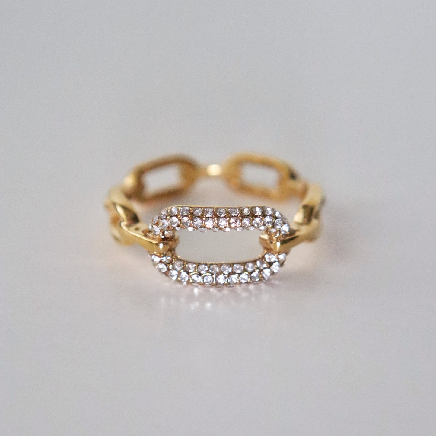 Gold ring with diamond accents on a light gray background